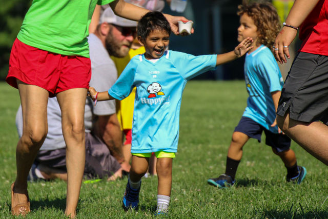 Young boy in a light blue jersey celebrating with arms outstretched at a HappyFeet soccer class