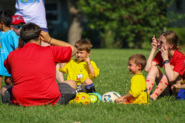 Coaches sitting with young players and yellow balls for a team talk near Roeland Park, KS
