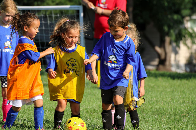 Kids chasing the ball in an outdoor soccer scrimmage at HappyFeet