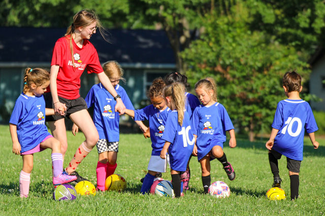 A coach leading a foot-on-ball drill with the team at a HappyFeet class near Parkville, MO